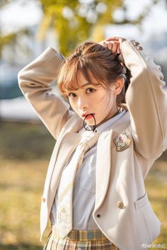 a young woman wearing a suit and tie holding her hair in one hand while posing for the camera