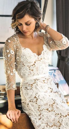 a woman in a white dress leaning on a table