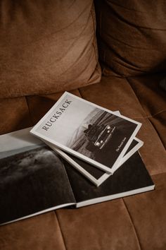 three black and white photographs sitting on top of a brown couch next to each other