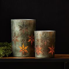 two metal vases sitting on top of a wooden table