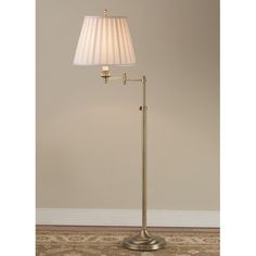 a floor lamp with a white shade on the base and a gold colored metal pole