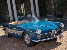 an old blue convertible car parked in front of a large building with columns and pillars