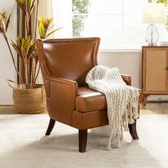 a chair with a blanket on it next to a potted plant and a window