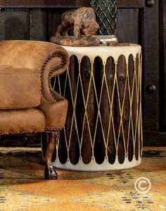 a brown chair sitting next to a table with a vase on it and a dog statue