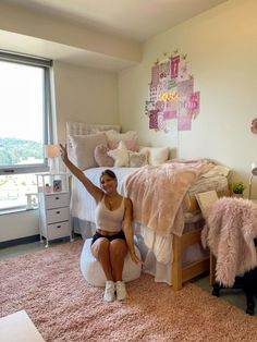 a woman sitting on top of a bed in a bedroom next to a large window