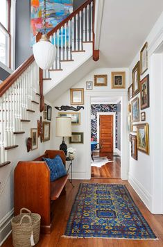 a hallway with pictures on the wall and a blue rug in front of the stairs