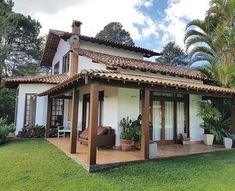 a white house sitting in the middle of a lush green field next to a palm tree