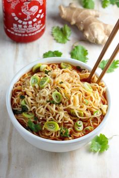 a bowl of noodles with chopsticks on a table next to ginger and garlic