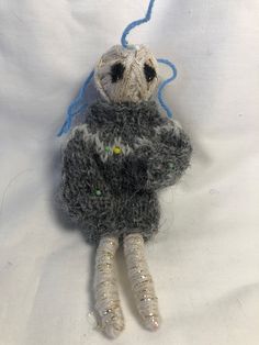 a small stuffed animal is sitting on a white sheet with blue thread in it's mouth