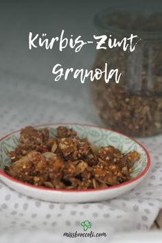 a bowl filled with granola sitting on top of a table next to a glass jar