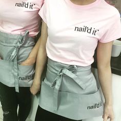 two women wearing matching aprons with the words nailed it written on them in black