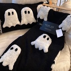 two black and white pillows with ghost faces on them, one has a price tag