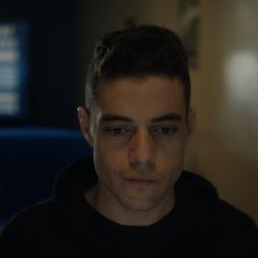 a man in a black hoodie looking at the camera with an intense look on his face