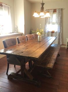 a large wooden table sitting in the middle of a living room next to a window