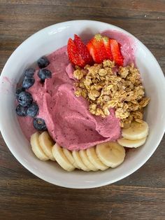 a bowl filled with fruit and granola on top of a wooden table