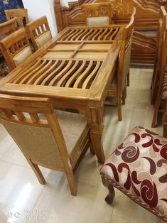 a wooden table with chairs and a footstool in a room filled with furniture