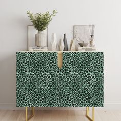 an animal print sideboard with vases and plants on top in a white room