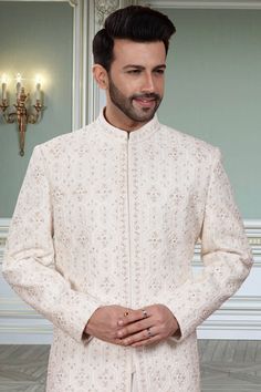 This Mens Sherwani (R14-S94) is the perfect attire for any groom with its beautifully crafted thread embroidery and stone embellishments. The intricate detailing adds a touch of elegance to this traditional garment. Its timeless design will make you stand out on your special day. Reception Nehru Jacket With Resham Embroidery And Traditional Drape, Nehru Jacket With Resham Embroidery For Reception, Bandhgala With Naqshi For Reception, Long Sleeve Sherwani With Resham Embroidery For Reception, Bandhgala With Dabka Work For Eid Reception, Traditional Resham Embroidery Bandhgala For Formal, Traditional Bandhgala With Resham Embroidery, Bollywood Style Nehru Jacket With Intricate Embroidery For Reception, Groom's Long Sleeve Embroidered Sherwani