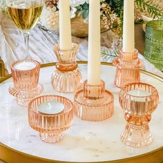 pink glass candlesticks on a table with flowers in the background