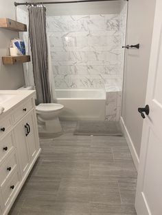 a white bathroom with marble tile flooring and walls