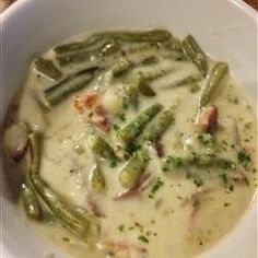 a white bowl filled with soup and green beans