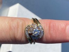 a person's hand with a ring on it that has blue and white stones