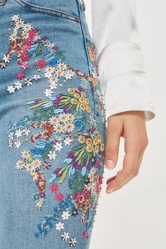 a close up of a person wearing jeans with flowers on them