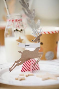 a paper reindeer on top of a plate next to some candy canes and milk