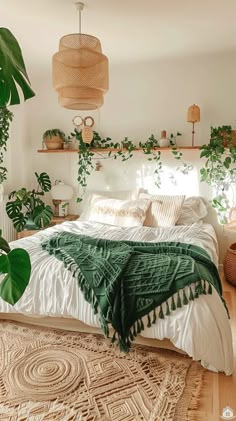 a bedroom with plants on the wall and a bed covered in blankets, pillows and blankets