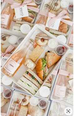 several plastic trays filled with different types of sandwiches and wine bottles on top of each other