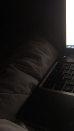 an open laptop computer sitting on top of a bed