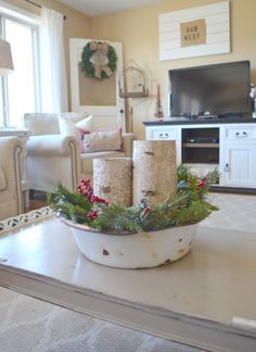 a white bowl filled with christmas greenery on top of a table in front of a tv