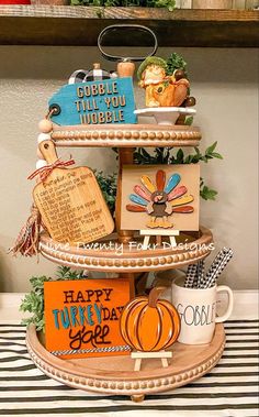 a three tiered tray with thanksgiving decorations on it