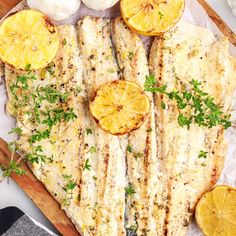 grilled fish with lemons and parsley on a cutting board