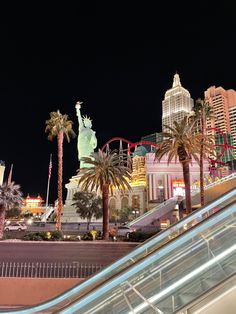 an escalator with palm trees in front of the las vegas strip at night