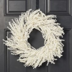 a white wreath is hanging on the front door