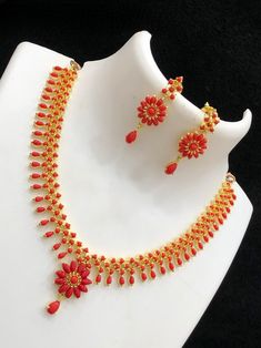 This Beautiful Gold Plated Elegant simple AD Red coral and pearl choker necklace Earring set offers an exquisite, delicate design. An alluring combination of tiny Marquis cut CZ color Ad stones and white pear shaped small pearls creates a stunning look. The set includes a matching pair of earrings, perfect for adding an extra touch of elegance. Coral Jewelry Set Kameswari Jewellers, Simple Coral Necklace Indian Gold, Red Choker Bridal Necklace For Celebration, Red Bridal Choker Necklace For Celebration, Red Choker Bridal Necklace For Party, Red Bridal Choker Necklace Gift, Red Bridal Choker Necklace For Party, Elegant Red Choker Jewelry Sets, Dainty Red Necklace For Wedding