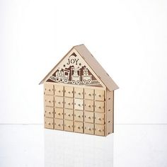 a wooden toy house with lots of drawers on the front and side, that says joy