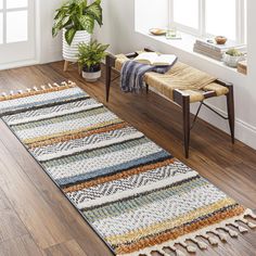 a large rug in the middle of a room with a bench and potted plant