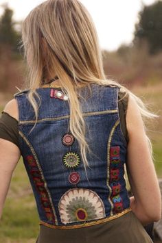 a woman wearing a denim vest with colorful patches on the back and buttons at the waist