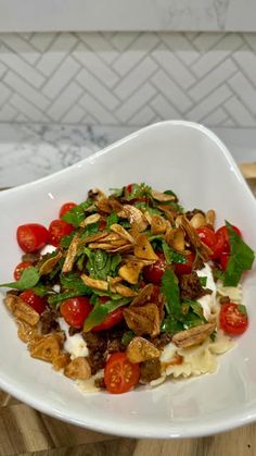 a white plate topped with pasta and veggies on top of a wooden table