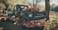 an old truck is decorated with flowers and pumpkins