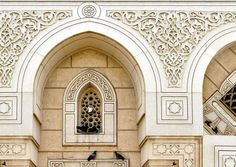 two birds are sitting on the ledges of a building with intricate carvings and windows