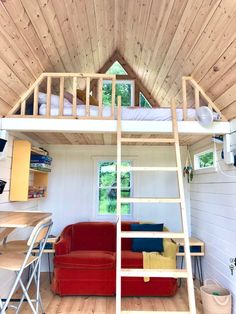 a loft bed with a red couch underneath it and a ladder to the top floor