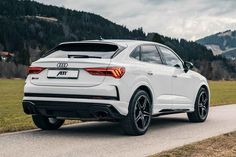 the rear end of a white audi q4 parked in front of a grassy field