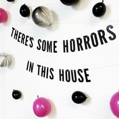 there's some horrors in this house sign on the wall with balloons around it