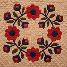 a quilted wall hanging with red and blue flowers on it's center piece