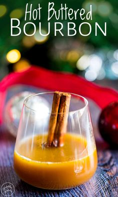 two cinnamon sticks sticking out of an orange liquid in a wine glass with the words hot buttered bourbon on it