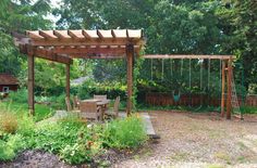 a wooden swing set in the middle of a yard with a table and chairs under it