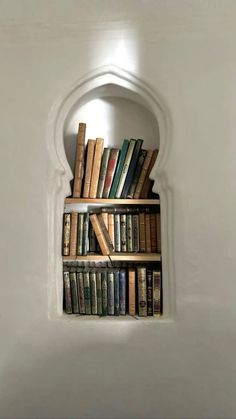 a bookshelf filled with lots of books sitting on top of a white wall